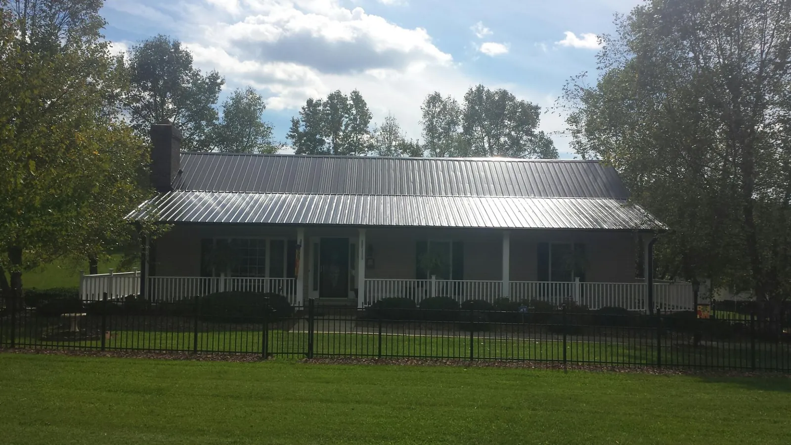 Gray metal roof on a brick ranch with a full width front porch — Gutter Guard Installation work by our crew in Bolivar