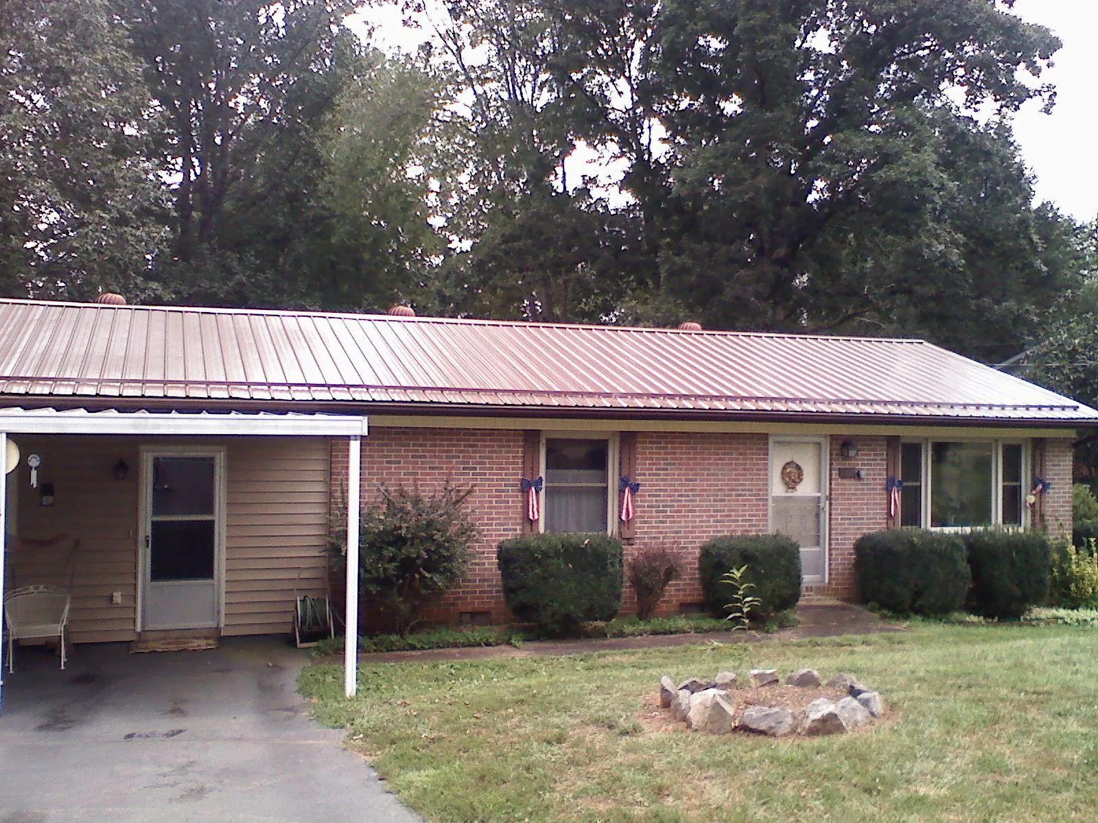 Bronze metal roof and carport on a brick ranch home — Roof Repair work by our crew in Bolivar