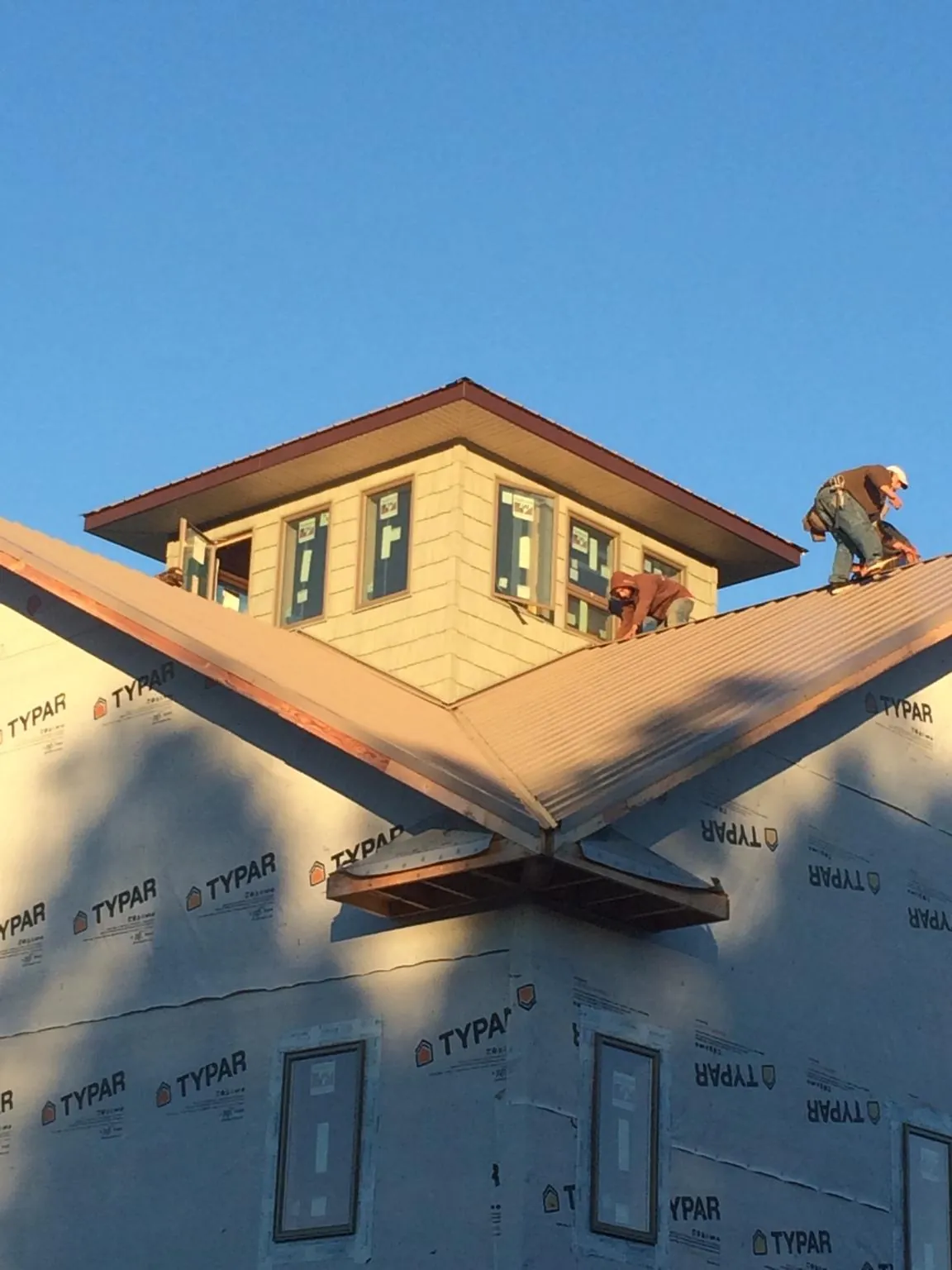 Roofers working around a rooftop cupola on a new metal roof at sunset — Roof Waterproofing in Bolivar by Roofing Brothers